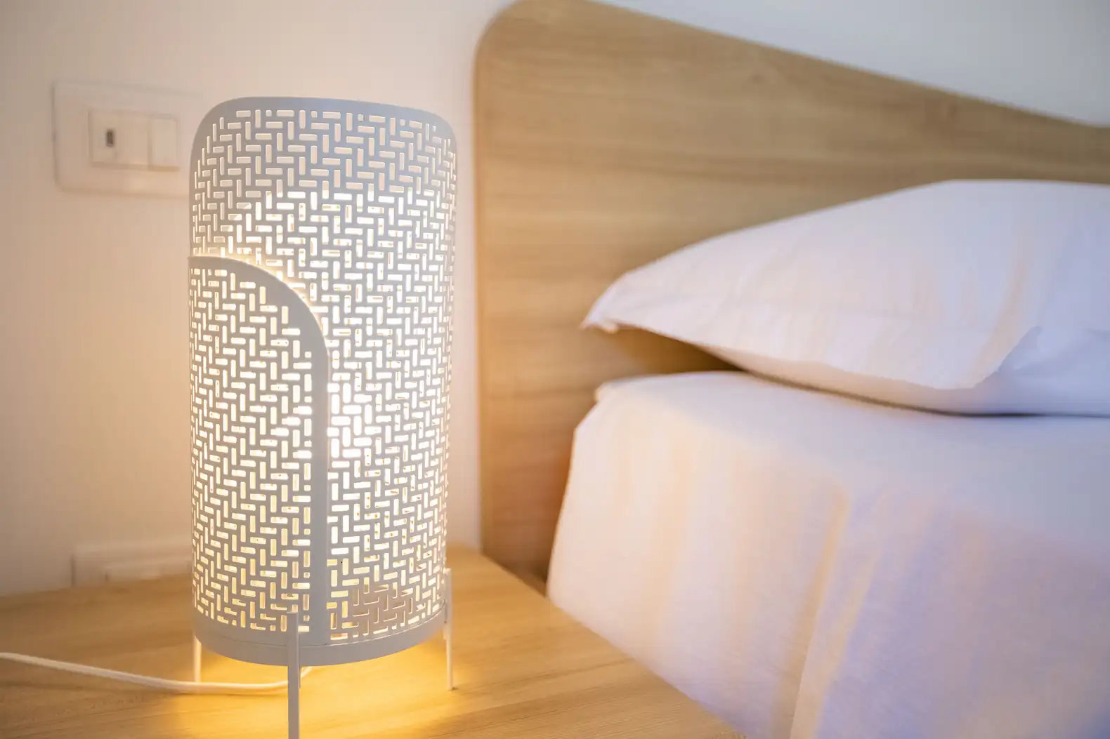 Dettaglio elegante del comodino, lampada e cucino nel nostro Glamping a Camping Carratois.